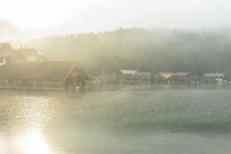 Mystical morning at Königssee in Schönau with boathouses. Sunrise and beautiful wafts of mist over