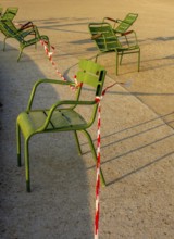Several green chairs are placed next to each other in the sun at Tuileries Garden. Red and white