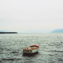 A rowing boat drifts quietly on the serene surface of Lake Geneva near Lausanne, Switzerland. The