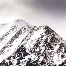 Snow-covered peaks of the Sancy massif rise dramatically against a moody sky in the Regional