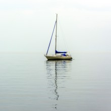 A sailing boat drifts smoothly over the serene waters of Lake Geneva, surrounded by a peaceful