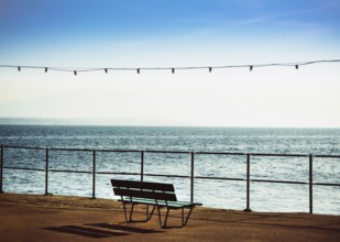 A bench is positioned along the promenade beside Geneva Lake in Nyon, Switzerland, providing a
