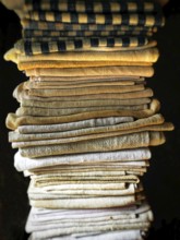 A neat stack of folded textiles in various shades of beige, cream, and a hint of black is