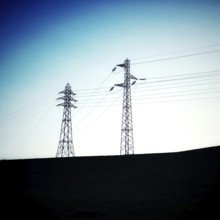 Two power towers reach upwards, silhouetted against a transitioning twilight sky. The horizon is