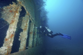 Diver exploring a derelict shipwreck in calm, clear water. Dive site wreck Le Donator, Giens