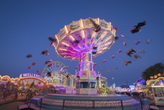 Brightly illuminated carousel at a night fair, chain carousel, spring festival, Cannstatter