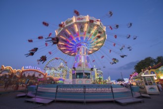 Colourful, illuminated carousel at night at a funfair, chain carousel, spring festival, Cannstatter