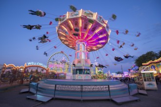 Luminous carousel turns on a colourful funfair, chain carousel, spring festival, Cannstatter