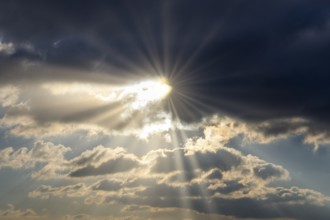 Dramatic rays of sunshine break through dark clouds in the sky, Baden-Württemberg, Germany