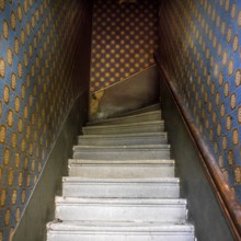 Staircase features worn steps and a dark atmosphere, going down to a lower level. The walls are