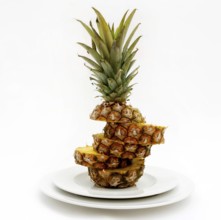 A carefully sliced pineapple is presented on white plates, highlighting its textured layers and
