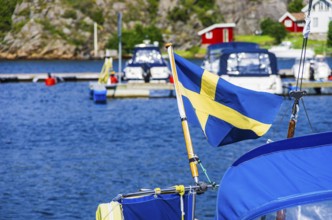 The Swedish flag flies at the stern of a boat in the marina of Henan on Orust, Bohuslän, Västra