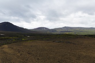 High plateau, barren volcanic landscape with snow fields, mountain peaks with rain clouds,