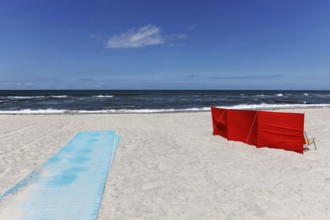 Deserted beach with red windbreak and blue sand mat for barrier-free beach access, blue sky, Baltic