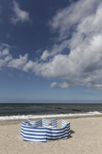 Deserted beach with person behind windbreak, blue sky, Baltic Sea near Kühlungsborn,