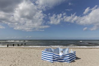 Deserted beach with person behind windbreak, blue sky, Baltic Sea near Kühlungsborn,