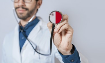 Doctor holding stethoscope with Malta flag. Malta health and care concept, Malta flag on