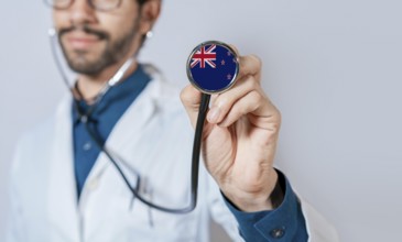 Doctor holding stethoscope with New Zealand flag. New Zealand health and care concept, New Zealand