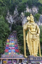 Murugan statue the God of War and colorful staircase leading to the caves with many pilgrims, Batu