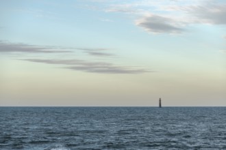 A lighthouse rises from the gentle waves of the ocean, surrounded by a tranquil seascape. Soft