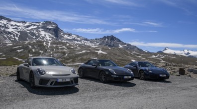 Three Porsche 911 sports cars parked on an Alpine road above the tree line, 911 991 GT3 on the