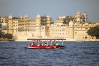 Excursion boat on Lake Pichola, behind the City Palace in the evening light, Udaipur, Rajasthan,