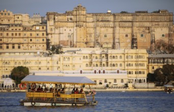 Electric excursion boat on Lake Pichola, behind the City Palace in the evening light, Udaipur,
