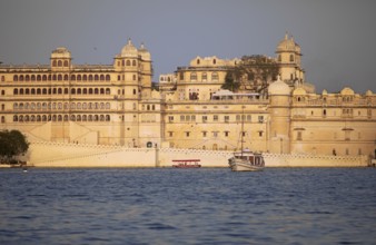 Excursion boats on Lake Pichola, behind the City Palace in the evening light, Udaipur, Rajasthan,