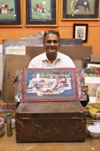 Miniature painter, 50 years old, shows a picture of the royal city palace in his studio, Udaipur,