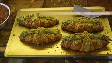 Four croissants decorated with pistachio cream on a golden tray, appetising and fresh, Agia Marina,