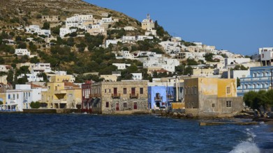 Colourful buildings along the coast with hills in the background, calm sea in the foreground, Agia