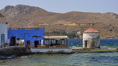 Restaurant Mylos, coastal landscape with blue buildings and a windmill by the sea, Agia Marina,