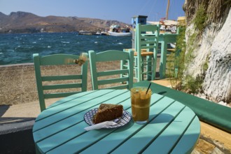 Cake and coffee on a green table by the sea, relaxing summer atmosphere with clear skies, Agia