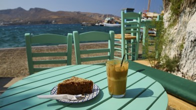 Turquoise-coloured table with drink and cake by the sea in sunny weather, relaxed atmosphere, Agia