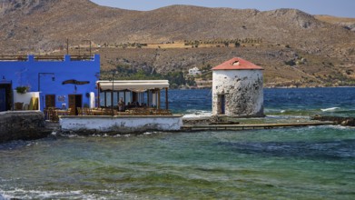 Restaurant Mylos, coastal village with windmill and blue buildings in front of mountain landscape,