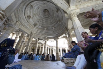 Indian woman praying between the white marble pillars in the Adinath temple in Ranakpur, Jain