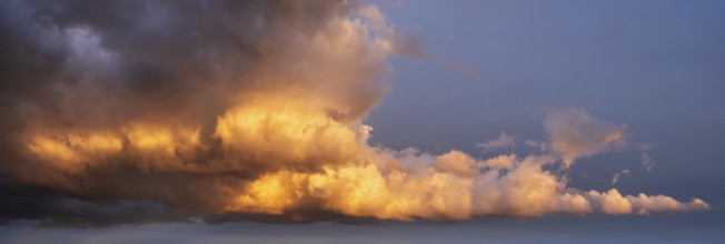 Background image for sky replacement, evening sky with dramatic illuminated dark clouds at sunset,