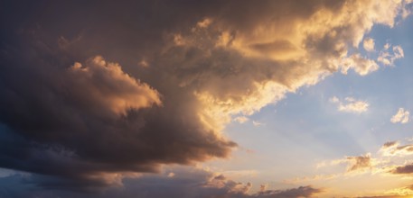 Background image for sky replacement, evening sky with illuminated dark clouds at sunset