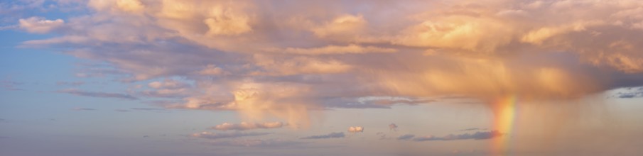 Background image for sky replacement, evening sky with illuminated clouds, rain shower and rainbow