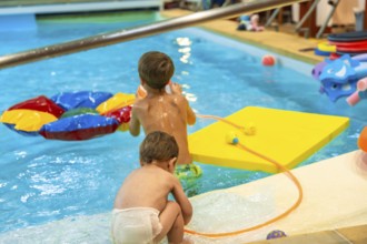 Two brothers enjoying playful moments with inflatable toys in a swimming pool, embracing the joy of