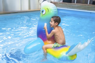 Happy child enjoying playful moments with a colorful inflatable seal in a sparkling pool during