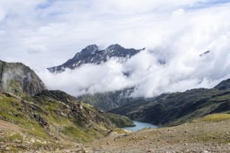 View of cloud-covered mountains and light blue mountain lake Trüber See in a barren mountain