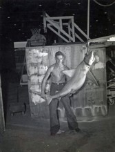 Man posing with shark. Grey reef shark (Carcharhinus amblyrhynchos, 1948