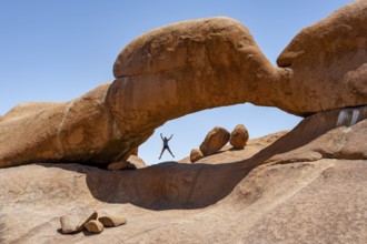 Tourist jumping in a rock arch, round rock formations with stone arch, Pontok Mountains, Great