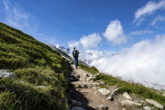 Mountaineer on a hiking trail, inversion weather situation with clouds in the valley, Chamonix,