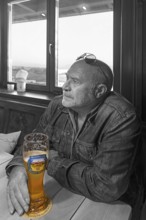 Elderly gentleman with sunglasses and wheat beer in a pub, black and white, Bavaria, Germany