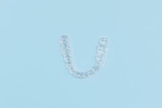 Top view of customized transparent dental teeth bite guard clear aligners for lower jaw on blue