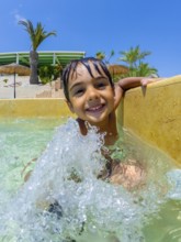 Smiling child splashing joyfully in a swimming pool, relishing carefree summer vacations at a