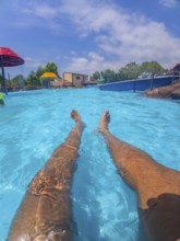 Pov shot of a man relaxing in a swimming pool at a water park, enjoying the summer sun and the