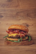 Burger with beef and bacon, with arugula and caramelized onions, pickles, sauce, homemade, no